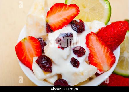 Obst- und Joghurtsalat gesundes Frühstück auf einem weißen Holztisch Stockfoto