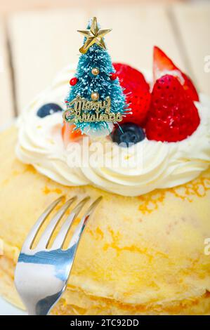 Weihnachtsbaum auf einem Pfannkuchenkrepé-Berg mit Schlagsahne und Erdbeere Stockfoto