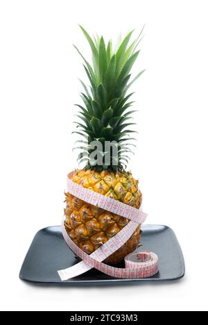 Ananas auf einer schwarzen Platte mit Bandmessgerät isoliert auf weißem Hintergrund Stockfoto