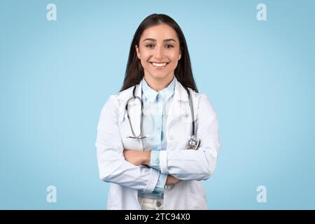 Positive weibliche Ärztin im weißen Laborkittel auf blauem Hintergrund Stockfoto