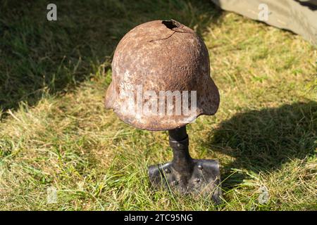 Ein rostiger, kaputter deutscher Militärhelm aus dem 2. Weltkrieg auf einem Infanterie-Spaten Stockfoto