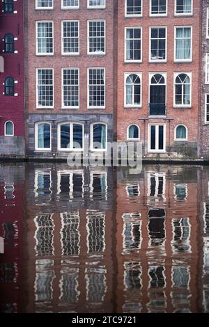 Alte Häuser in Amsterdam, Niederlande, spiegeln sich im Wasser eines Kanals Stockfoto