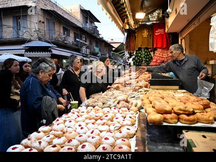 Jerusalem, Israel. Dezember 2023. Die Menschen kaufen Sufganiyot, einen frittierten, mit Gelee gefüllten Donut, in der fünften Nacht des jüdischen Feiertags von Hanukka, dem Lichterfest, auf dem Mahane Yehuda Markt in Jerusalem, am Montag, den 11. Dezember 2023. Der achttägige Hanukka-Feiertag erinnert an den Sieg der Makkabäer über das griechisch-syrische Königreich und die Wiedereinweihung des Zweiten Tempels. Foto: Debbie Hill/ Credit: UPI/Alamy Live News Stockfoto