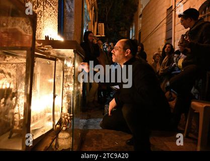 Jerusalem, Israel. Dezember 2023. Ein orthodoxer Jude zündet am Montag, den 11. Dezember 2023, in der fünften Nacht des jüdischen Feiertags von Hanukka, dem Lichterfest, in Nachlaot in Jerusalem eine Hanukkiya an. Der achttägige Hanukka-Feiertag erinnert an den Sieg der Makkabäer über das griechisch-syrische Königreich und die Wiedereinweihung des Zweiten Tempels. Foto: Debbie Hill/ Credit: UPI/Alamy Live News Stockfoto