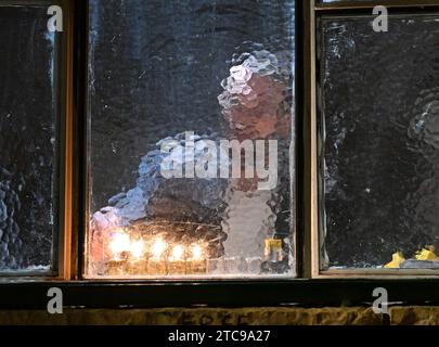 Jerusalem, Israel. Dezember 2023. Ein Ultra-orthodoxer Jude zündet eine Hanukkiya an der fünften Nacht des jüdischen Feiertags von Hanukka, dem Lichterfest, in Nachlaot in Jerusalem, am Montag, den 11. Dezember 2023. Der achttägige Hanukka-Feiertag erinnert an den Sieg der Makkabäer über das griechisch-syrische Königreich und die Wiedereinweihung des Zweiten Tempels. Foto: Debbie Hill/ Credit: UPI/Alamy Live News Stockfoto