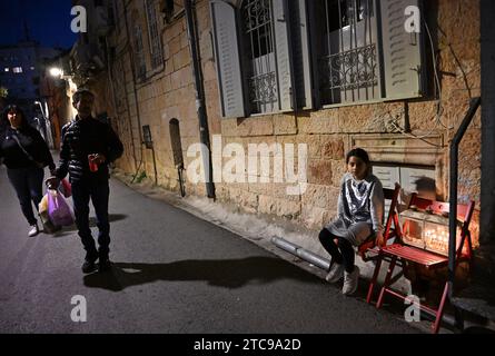 Jerusalem, Israel. Dezember 2023. Ein israelisches Mädchen sitzt neben einer Hanukkiya, in der fünften Nacht des jüdischen Feiertags von Hanukka, dem Lichterfest, in Nachlaot in Jerusalem, am Montag, den 11. Dezember 2023. Der achttägige Hanukka-Feiertag erinnert an den Sieg der Makkabäer über das griechisch-syrische Königreich und die Wiedereinweihung des Zweiten Tempels. Foto: Debbie Hill/ Credit: UPI/Alamy Live News Stockfoto