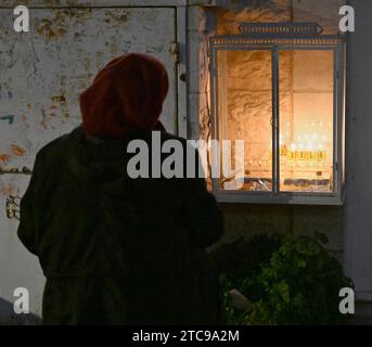 Jerusalem, Israel. Dezember 2023. Eine Frau betet vor den Lichtern in einer Hanukkiya, in der fünften Nacht des jüdischen Feiertags von Hanukka, dem Lichterfest, in Nachlaot in Jerusalem, am Montag, den 11. Dezember 2023. Der achttägige Hanukka-Feiertag erinnert an den Sieg der Makkabäer über das griechisch-syrische Königreich und die Wiedereinweihung des Zweiten Tempels. Foto: Debbie Hill/ Credit: UPI/Alamy Live News Stockfoto