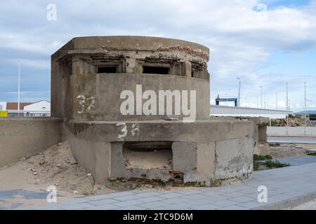 Alter Militärbunker aus Beton mit verwitterten Wänden, in einem städtischen Gebiet unter bewölktem Himmel. Stockfoto