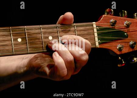 Bild eines Musikers, der einen Akkord am Gitarrenhals spielt Stockfoto