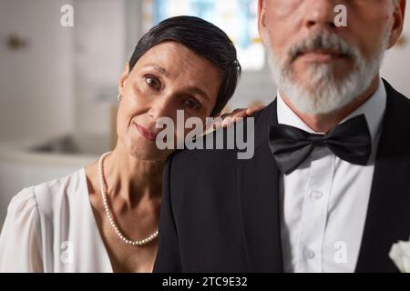 Nahporträt einer eleganten älteren Frau als Braut, die Kopf auf der Schulter des Bräutigams legt und lächelt Stockfoto