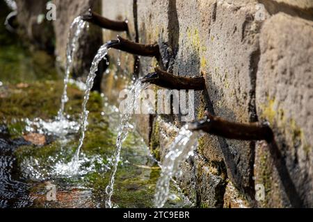 Nahaufnahme einiger Wasserstrahlen in einem alten rustikalen Brunnen an einem sonnigen Tag Stockfoto