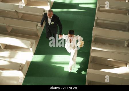 Über dem Blick auf das frisch vermählte Seniorenpaar, das gemeinsam in der Kirche durch Sonnenlicht geht, Kopierraum Stockfoto