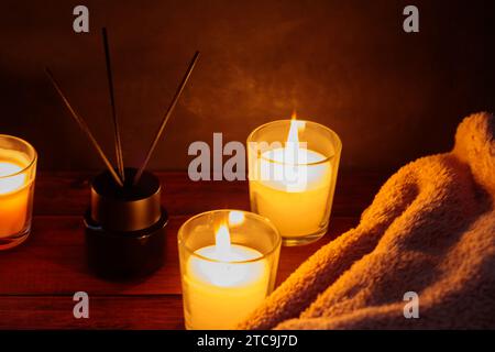 Beruhigende Aromatherapie mit Schilfdiffusor, Decke und Kerzen auf Holztisch Stockfoto