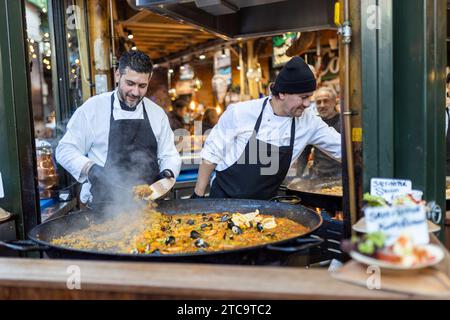 LONDON, Großbritannien - 10. Dezember 2023 männliche Verkäufer bereiten Paella auf dem Borough Market zu Stockfoto