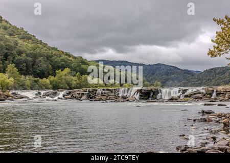 Ein malerischer Blick im Freien mit einem Fluss, der sich durch üppige grüne Hügel schlängelt, mit Bäumen und Felsen, die in der gesamten Landschaft verstreut sind Stockfoto