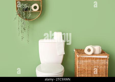 Toilettenschüssel und Wäschekorb mit Papierrollen in der Nähe der Farbwand Stockfoto