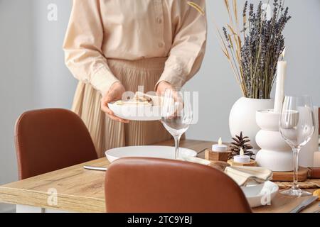 Frau, die einen Tisch mit getrockneten Blumen im Esszimmer legt Stockfoto