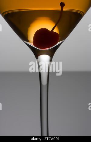 Manhattan Cocktail mit Kirschgarnitur aus nächster Nähe auf grauem Hintergrund Stockfoto