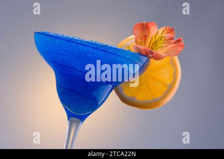 Blue Hawaiian Mischgetränk mit Orchideen und orange garnieren auf einfarbigen Hintergrund Stockfoto