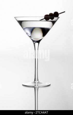 Martini-Cocktail mit Oliven-Silhouette auf hellgrauem Hintergrund Stockfoto