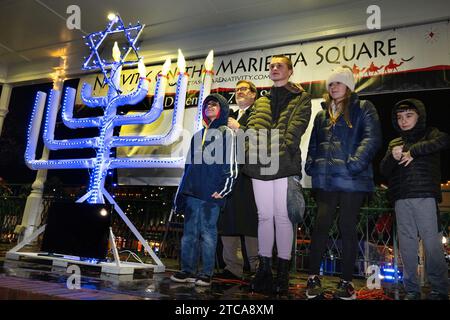 Marietta, GA, USA. Dezember 2023. Rabbi Joseph Prass wird von Studenten aus der Region begleitet, die die Menschenmenge im Glover Park leiten, um die Menora in der vierten Nacht von Hanukka anzuzünden. (Kreditbild: © Robin Rayne/ZUMA Press Wire) NUR REDAKTIONELLE VERWENDUNG! Nicht für kommerzielle ZWECKE! Stockfoto