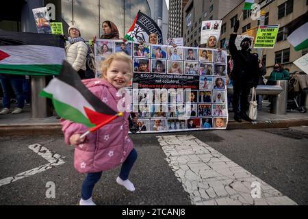 NEW YORK, NEW YORK - 11. DEZEMBER: Ein zweijähriges Mädchen aus Queens, New York, namens Layla, läuft mit palästinensischer Flagge vor den Vereinten Nationen während eines weltweiten Aufrufs zum „Strike for Palestine“ am 11. Dezember 2023 in New York City. Die Proteste sind auf der ganzen Welt nach Israels unerbittlicher Vergeltungsbombardierung von Gaza fortgesetzt worden, nachdem die militante Gruppe Hamas am 7. Oktober einen tödlichen Angriff in Südisrael gestartet hatte. Das Gesundheitsministerium im Gazastreifen sagte, dass die Zahl der Todesopfer seit Beginn des israelisch-Hamas-Konflikts über 17.700 Menschen liegt, etwa zwei Drittel davon Frauen und Kinder. (Pho Stockfoto