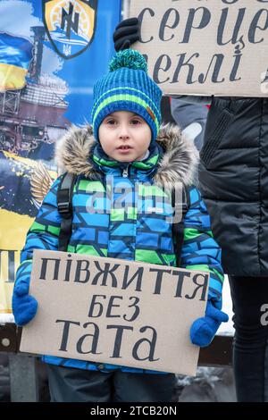 Lviv, Ukraine. Dezember 2023. Der Junge mit dem Poster "ein halbes Leben ohne Vater" steht im Zentrum von Lemberg. Verwandte und Freunde von Gefangenen des Asov-Regiments nehmen an der alles ukrainischen Aktion „sei nicht still! Töte dich! Die Ukraine wartet auf die Rückkehr ihrer Helden in die Heimat", in Lemberg, Ukraine? Sie versammelten sich, um an die gefangenen Verteidiger von Mariupol zu erinnern, die seit 19 Monaten in russischer Gefangenschaft sind und dort gefoltert werden. Gleichzeitig fand eine solche Aktion in vielen Städten der Ukraine statt. Quelle: SOPA Images Limited/Alamy Live News Stockfoto