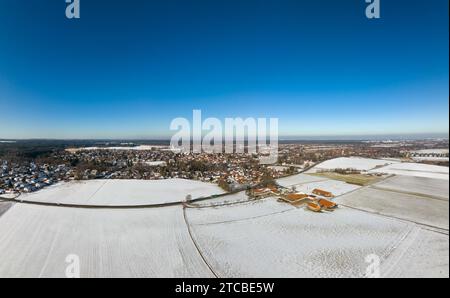 Großer Panoramablick auf eine Winterlandschaft mit schneeweißen Feldern und einem Dorf im Hintergrund Stockfoto
