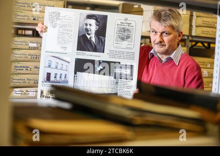 PRODUKTION - 17. November 2023, Sachsen, Falkenstein: Ralph IDE steht mit einem Ausstellungsplakat über Alfred Roßner im Falkensteiner Stadtarchiv. Roßner, geboren in der Vogtländer Kleinstadt, rettete während der NS-Zeit mehrere Juden, indem er sie versteckte oder ihnen die Flucht als Treuhänder einer Textilfabrik in Polen ermöglichte. Die Gestapo erfuhr von seinen Aktivitäten und verhaftete ihn. Er starb vor 80 Jahren im Dezember 1943 im Gefängnis im heutigen Sosnowiec. Er trägt den Ehrentitel „gerecht unter den Nationen“ von der israelischen Gedenkstätte Yad Vashem. (An dpa ''Oskar Schind Stockfoto