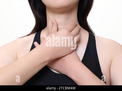 Eine Frau, die an Ösophagitis leidet, berührt ihren zerknitterten Hals. Stockfoto