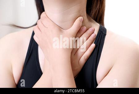 Eine Frau, die an Ösophagitis leidet, berührt ihren zerknitterten Hals. Stockfoto