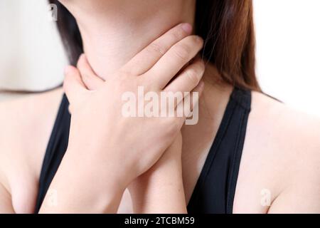 Eine Frau, die an Ösophagitis leidet, berührt ihren zerknitterten Hals. Stockfoto