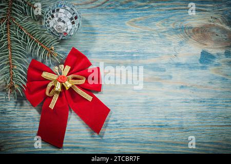 Rote Weihnachtsschleife mit Glockendisco-Ball Tannenbrunch auf Holzbrett Celebration Concept Stockfoto