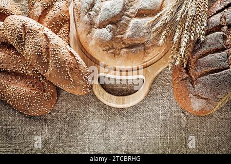 Schwarzbrot-Brotschneidebrett Weizenohren auf hessischem Hintergrund Stockfoto