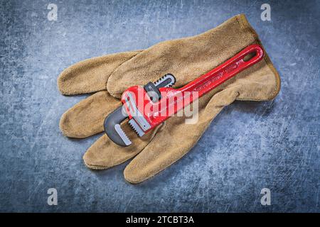 Affenschlüssel Lederschutzhandschuhe auf zerkratztem metallischem Hintergrund Sanitärkonzept Stockfoto