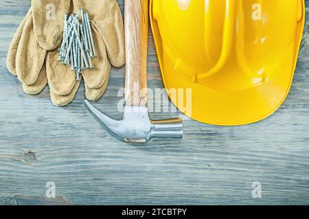 Konstruktionshelm Lederschutzhandschuhe Klaue Hammer Nägel auf Holzbrett Konstruktionskonzept Stockfoto