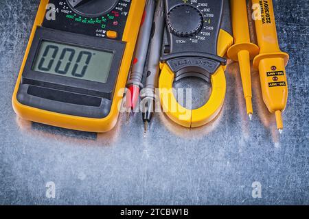 Zusammensetzung des digitalen Strommesszangen-Elektromessgerätes am metallischen Hintergrundstromkonzept Stockfoto