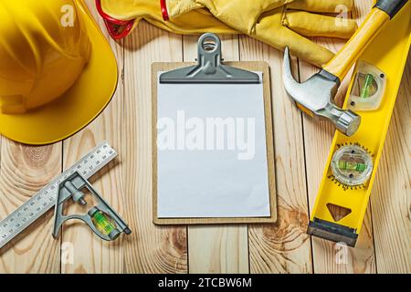 Leeres Papierblatt für Ihren Text in der Zwischenablage und Bauwerkzeuge auf Holz Stockfoto