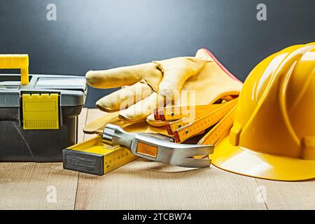 Schwarze Werkzeugkastenhandschuhe Hammer Level Holz Meter Helm Stockfoto
