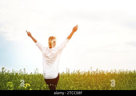 Die Schönheit eines Mädchens im Freien, die Natur und Freiheit genießen und das Leben genießen. Schönes Mädchen in einem weißen Hemd, schlendert auf einem Frühlingsfeld, die Sonne Stockfoto