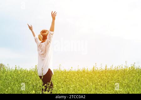 Die Schönheit eines Mädchens im Freien, die Natur und Freiheit genießen und das Leben genießen. Schönes Mädchen in einem weißen Hemd, schlendert auf einem Frühlingsfeld, die Sonne Stockfoto