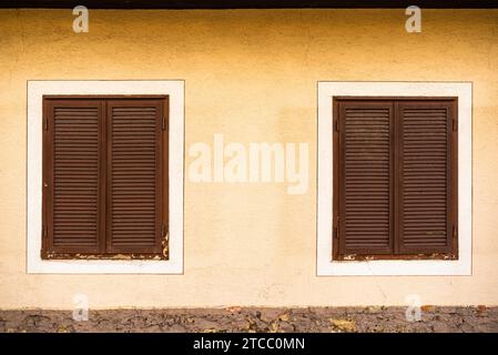 Zwei Holzfenster mit braunen Fensterläden auf österreichischen Haus. Hintergrund tradition Konzept Stockfoto