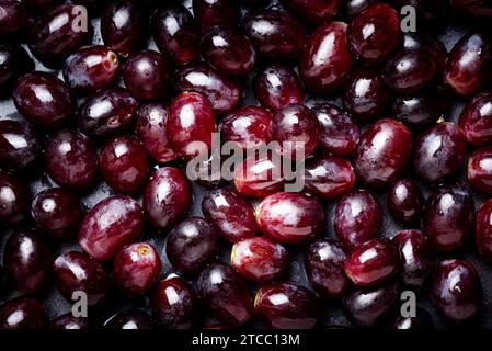 Hintergrund von roten Trauben bedeckt mit Wassertropfen. Dunkles lebhaftes Design Stockfoto