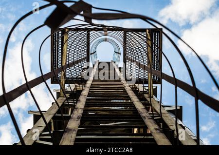 Alte, rostige Treppe mit Schäden an blauem Himmel und Wolken Stockfoto