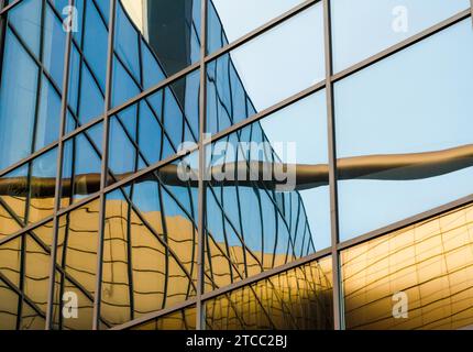 Verzerrte Reflexion eines gelben Gebäudes in den Spiegelfenstern eines Bürogebäudes Stockfoto