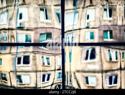 Krumme Reflexion von Häusern im Glas des Fensters abstrakt farbiger Hintergrund Stockfoto