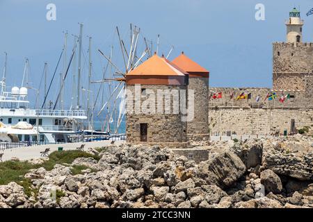 Mandraki Hafen in Rhodos Stadt mit alten Windmühlen und Kastell Agios Nikolaos mit Leuchtturm auf der griechischen Insel Rhodos Stockfoto