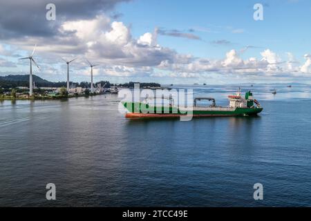 Hafen Victoria auf der seychellischen Insel mahe mit Frachtschiff vorne und Windrädern im Hintergrund Stockfoto