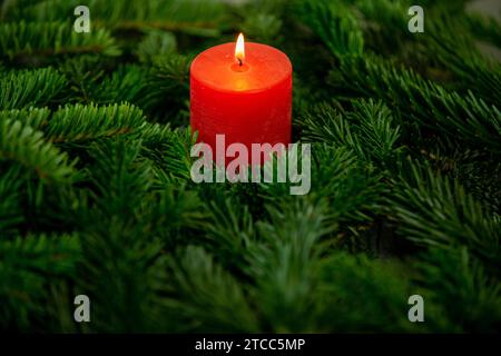 Weihnachtsmotiv, Textur, Tapete, Hintergrund mit Zweigen einer Nordmanntanne und brennender roter Kerze auf grauem Marmorhintergrund Stockfoto