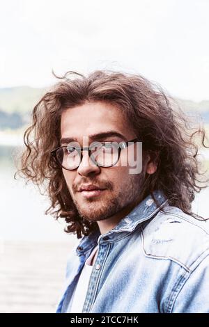 Porträt eines hübschen jungen Mannes mit langen Haaren, Brille und Bart Stockfoto